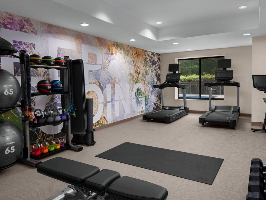A gym with exercise equipment, a treadmill, and a rowing machine.