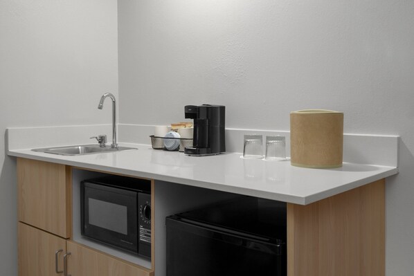 A compact kitchen with a sink, coffee maker, and two glasses on the counter.