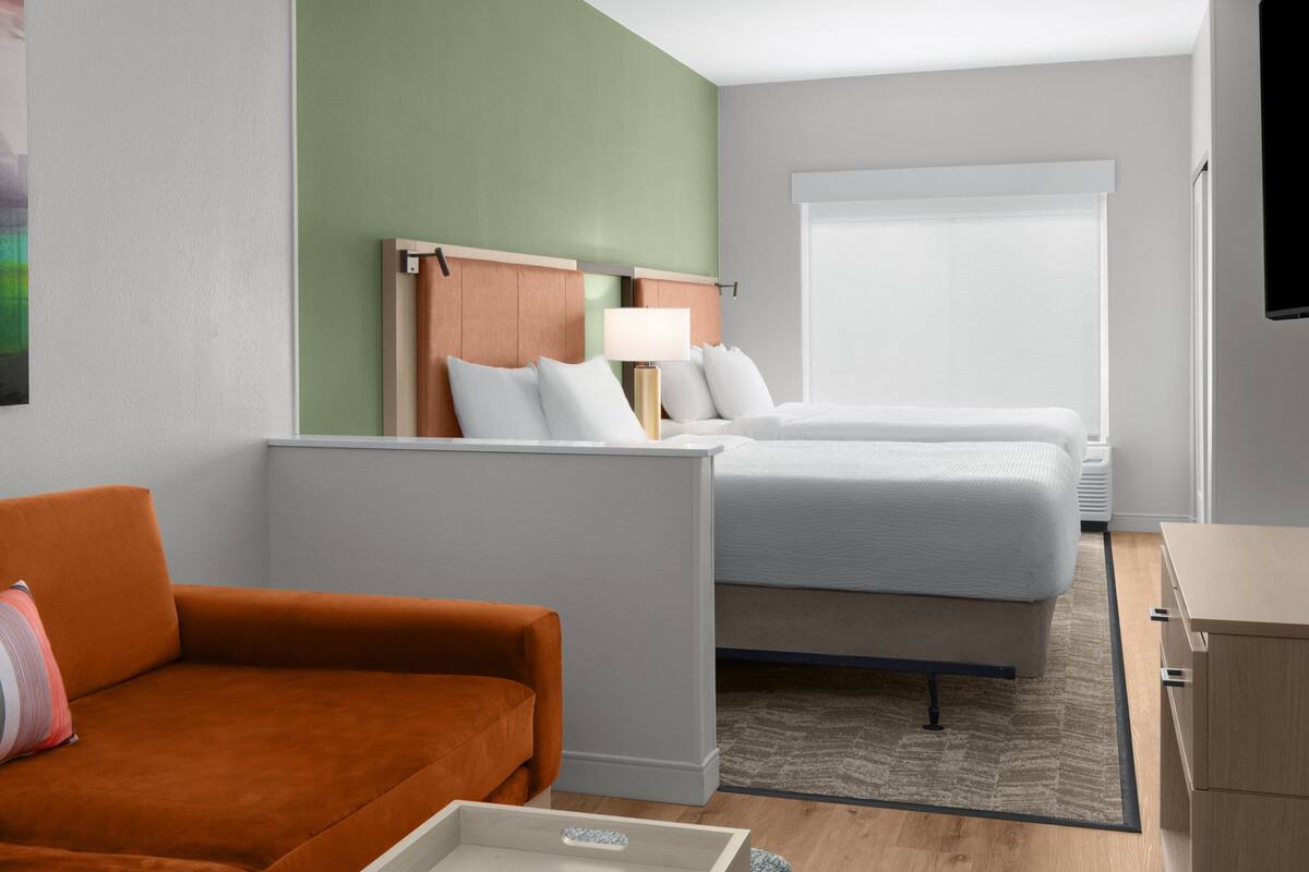 A hotel room with a bed, a sofa, a desk, and a TV.