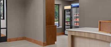 A reception area with a wooden reception desk, a glass door leading outside, and a refrigerator stocked with beverages.