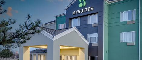A modern hotel with a prominent 'MYSUITES' sign, a covered entrance, and a well-maintained exterior.