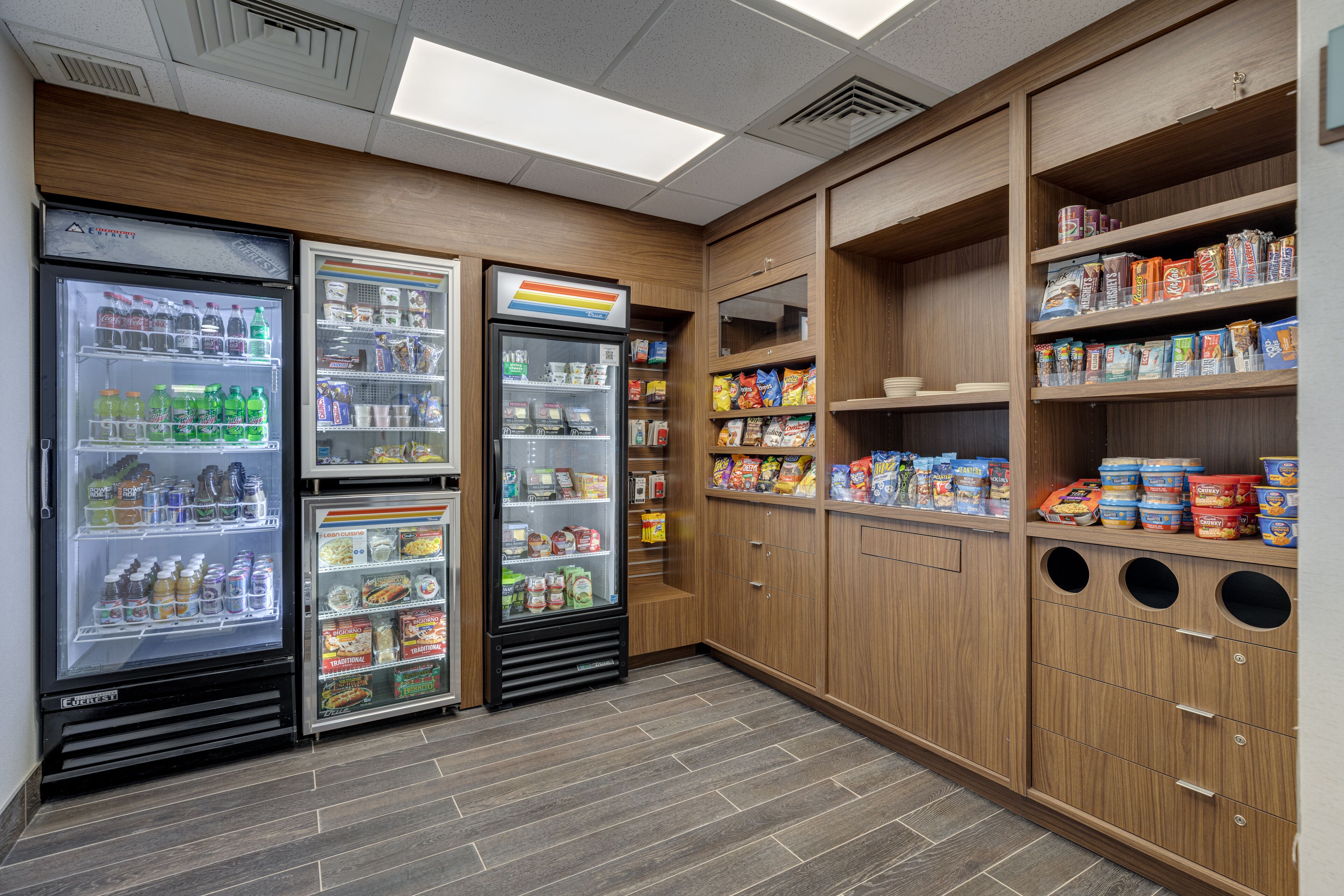 Un coin d’un magasin avec des distributeurs de boissons réfrigérés, des étagères à collations et des armoires de rangement.
