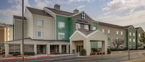 A multi-story hotel with a green and beige facade, a prominent 'MYSUITES' sign, and a covered entrance area.