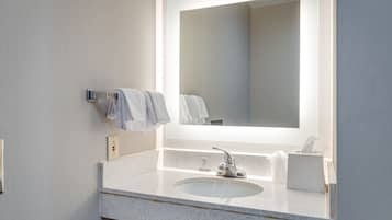A modern bathroom with a large mirror, a sink, and a towel rack.