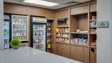 A kitchenette with a refrigerator, a freezer, and a microwave. There is a small plant on the counter.