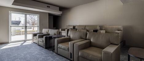 A modern living room with a sectional sofa, a small table, and a large sliding glass door leading to an outdoor balcony.