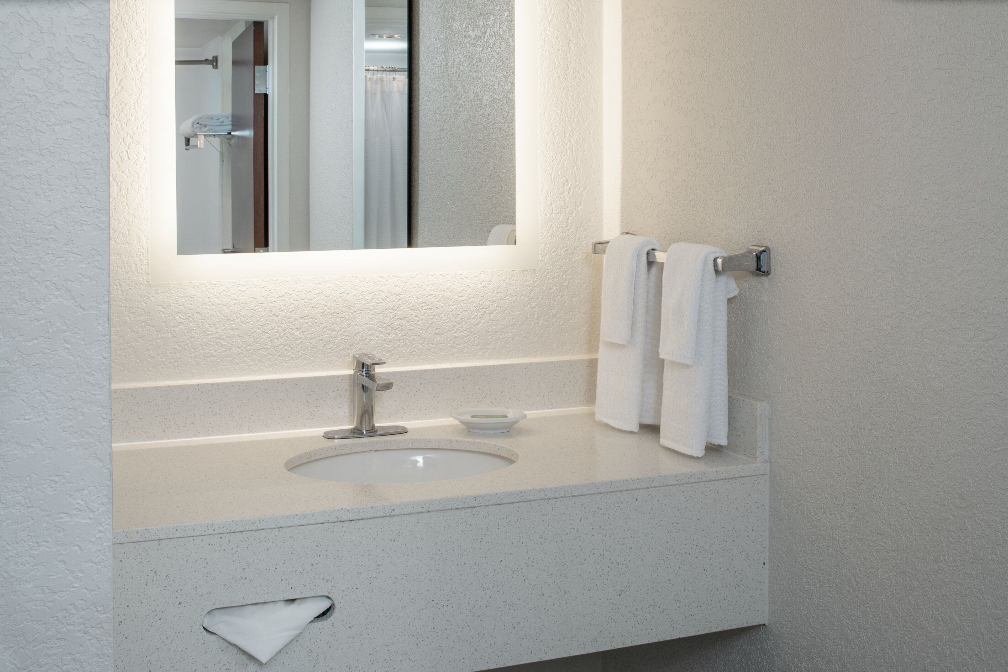 Une salle de bain avec un lavabo blanc, un miroir et un porte-serviettes.