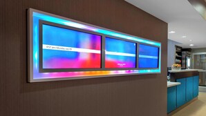 A modern hotel reception area with a digital display showing the time and date. - Springhill Suites Memphis East / Galleria (Memphis)