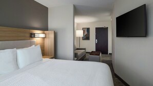 Une chambre d’hôtel avec un grand lit, un téléviseur à écran plat fixé au mur, une table de chevet et une lampe.