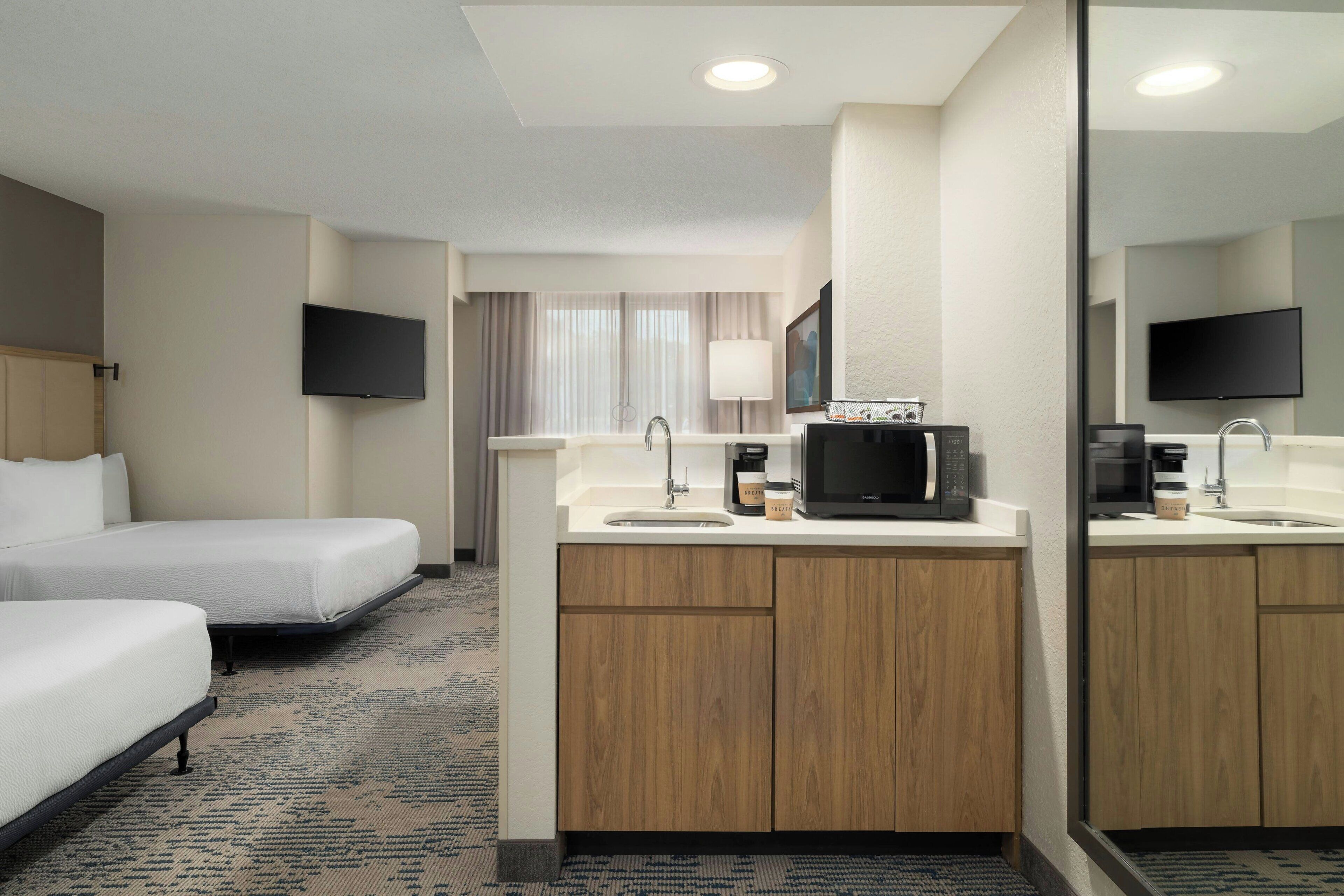 Une chambre d’hôtel comprenant un lit, une petite kitchenette équipée d’un four à micro-ondes, d’une machine à café et d’un téléviseur.