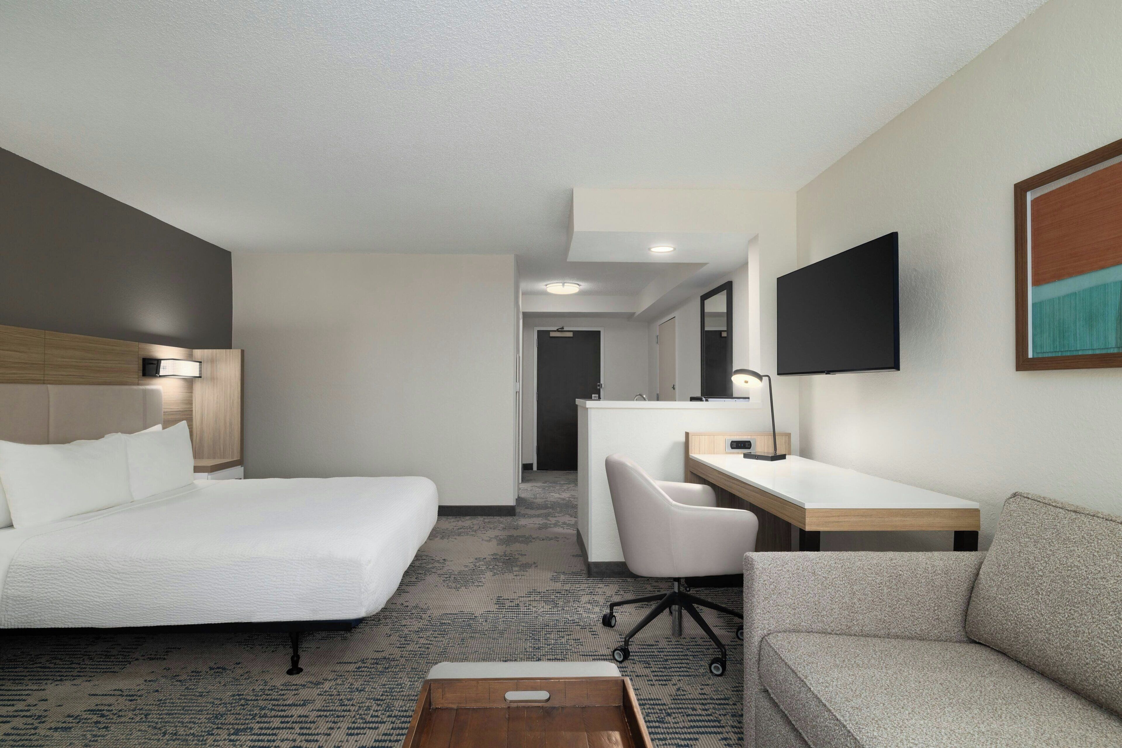 Een hotelkamer met een bed, een bureau, een stoel, een bank en een televisie.