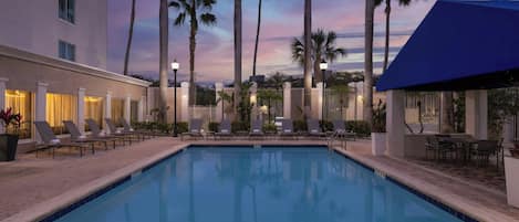 Una piscina al aire libre, sombrillas, sillones reclinables de piscina