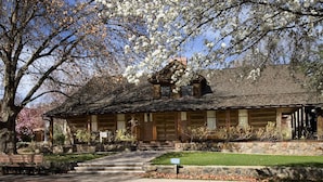 Ein rustikales Holzhaus mit Steinunterbau, einer Holzterrasse und einem gepflegten Rasen.