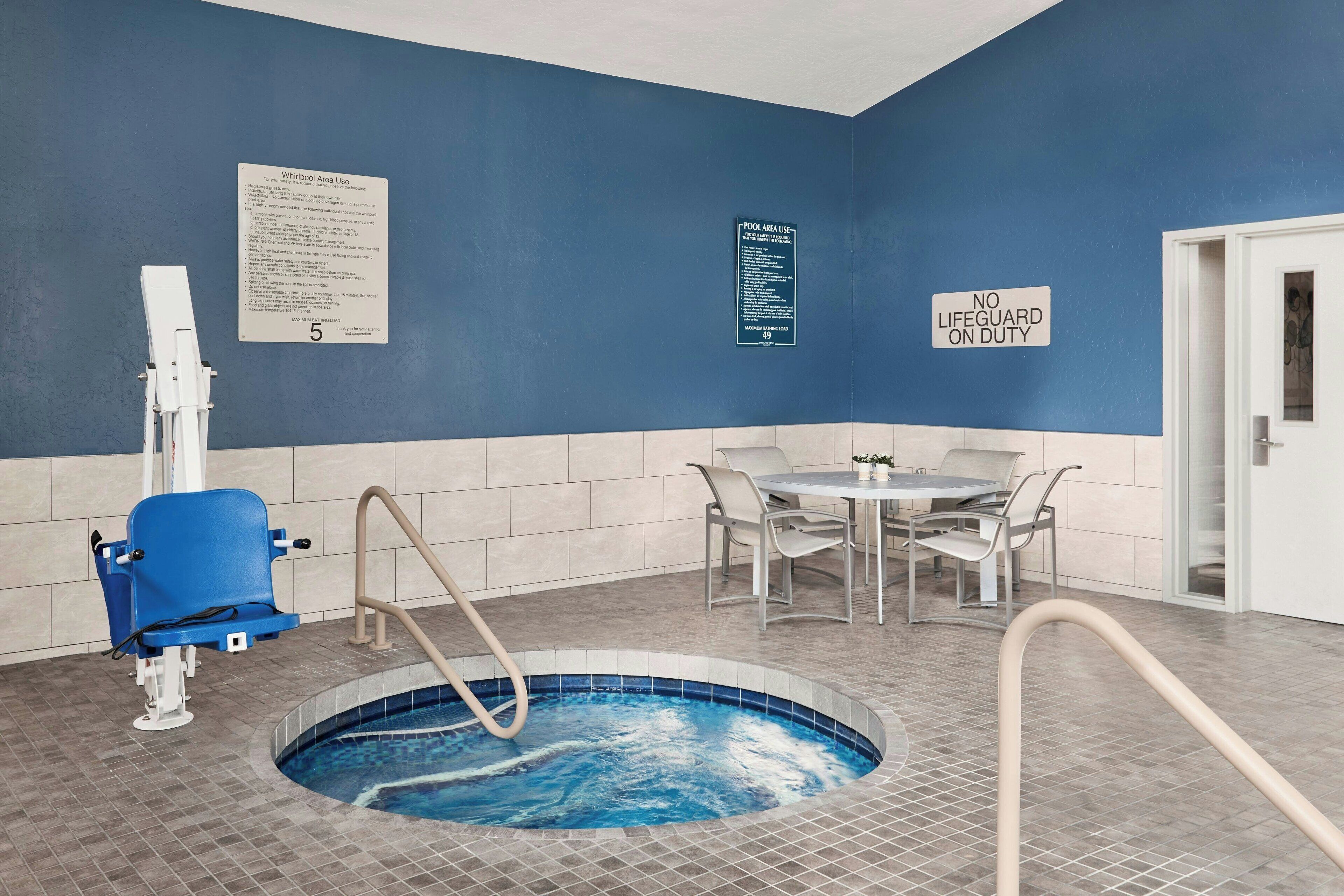A swimming pool area with a blue wall, a lifeguard sign, and a pool area use sign.