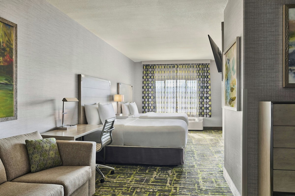 A hotel room with a bed, a sofa, a desk, and a TV.