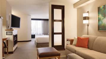 Una habitación de hotel con cama, televisor, escritorio, sofá y un cuadro en la pared.