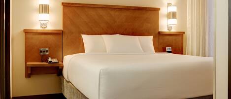 A hotel room with a large bed, wooden headboard, bedside lamps, and a telephone on a nightstand.
