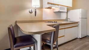 Una cocina compacta con comedor, que incluye una mesa, sillas, un microondas y un refrigerador.