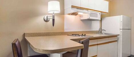 Une cuisine compacte avec un coin repas comprenant une table, des chaises, un four à micro-ondes et un réfrigérateur.