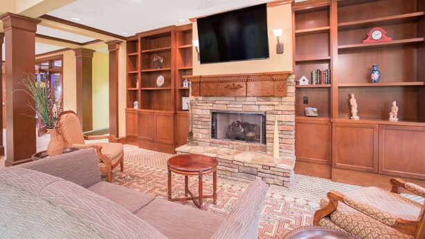 A living room with a fireplace, comfortable seating, and a large TV mounted above it. - Hawthorn Extended Stay by Wyndham Conyers (Conyers)