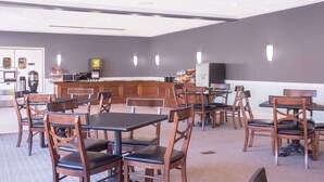 A restaurant with wooden tables and chairs, a bar area, and a kitchen in the background. - Hawthorn Extended Stay by Wyndham Conyers (Conyers)