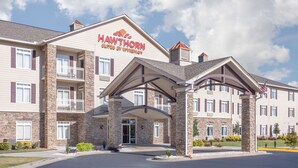 A multi-story hotel with a stone facade, a covered entrance, and an American flag. - Hawthorn Extended Stay by Wyndham Conyers (Conyers)
