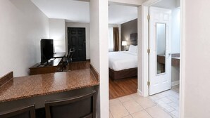 A hotel room with a bed, a desk with a chair, a TV, a door, and a bathroom visible through an open door. - Quality Inn Augusta West Near Fort Gordon (Augusta)