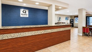 A hotel reception desk with a blue wall and a sign that reads 'Quality by Choice Hotels.' - Quality Inn Augusta West Near Fort Gordon (Augusta)
