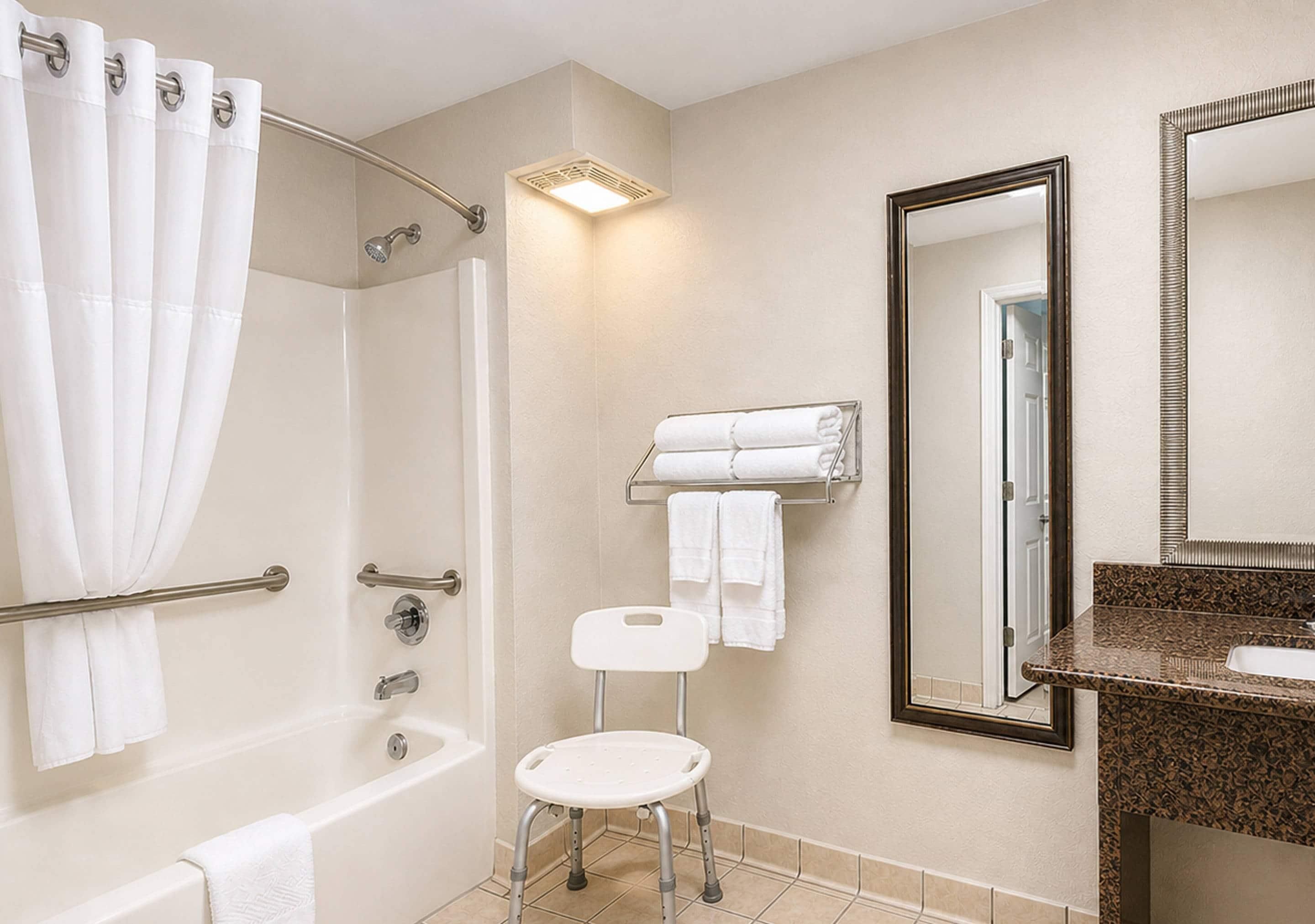 Un baño con ducha, inodoro, lavabo, espejo y perchero para toallas.