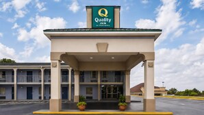 A hotel entrance with a sign reading 'Quality Inn by Choice Hotels,' a covered walkway, and a parking lot. - Quality Inn Augusta West Near Fort Gordon (Augusta)