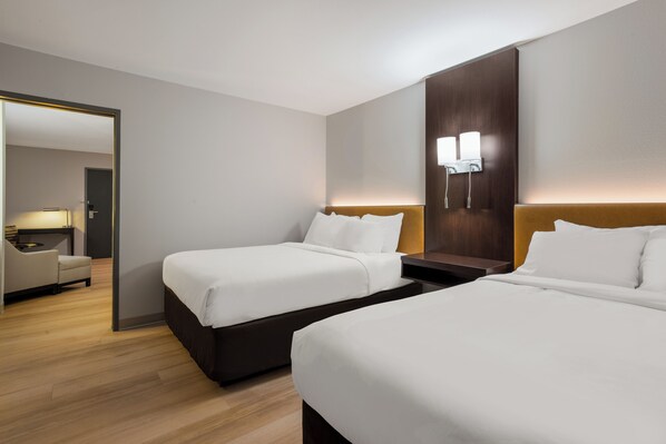 Habitación de hotel con dos camas, un escritorio y una silla.