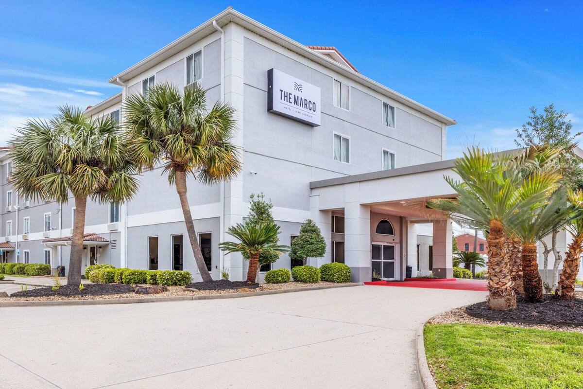 A modern hotel building with a sign reading "The Marco Hotel & Spa."