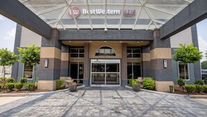 The exterior of a Best Western Plus hotel with a modern design, featuring a glass entrance canopy and a paved driveway.