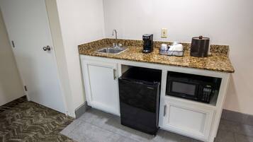 A compact kitchen with a sink, coffee maker, microwave, and refrigerator.