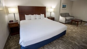A hotel room with a large bed, two bedside tables, a chair, and a small table.