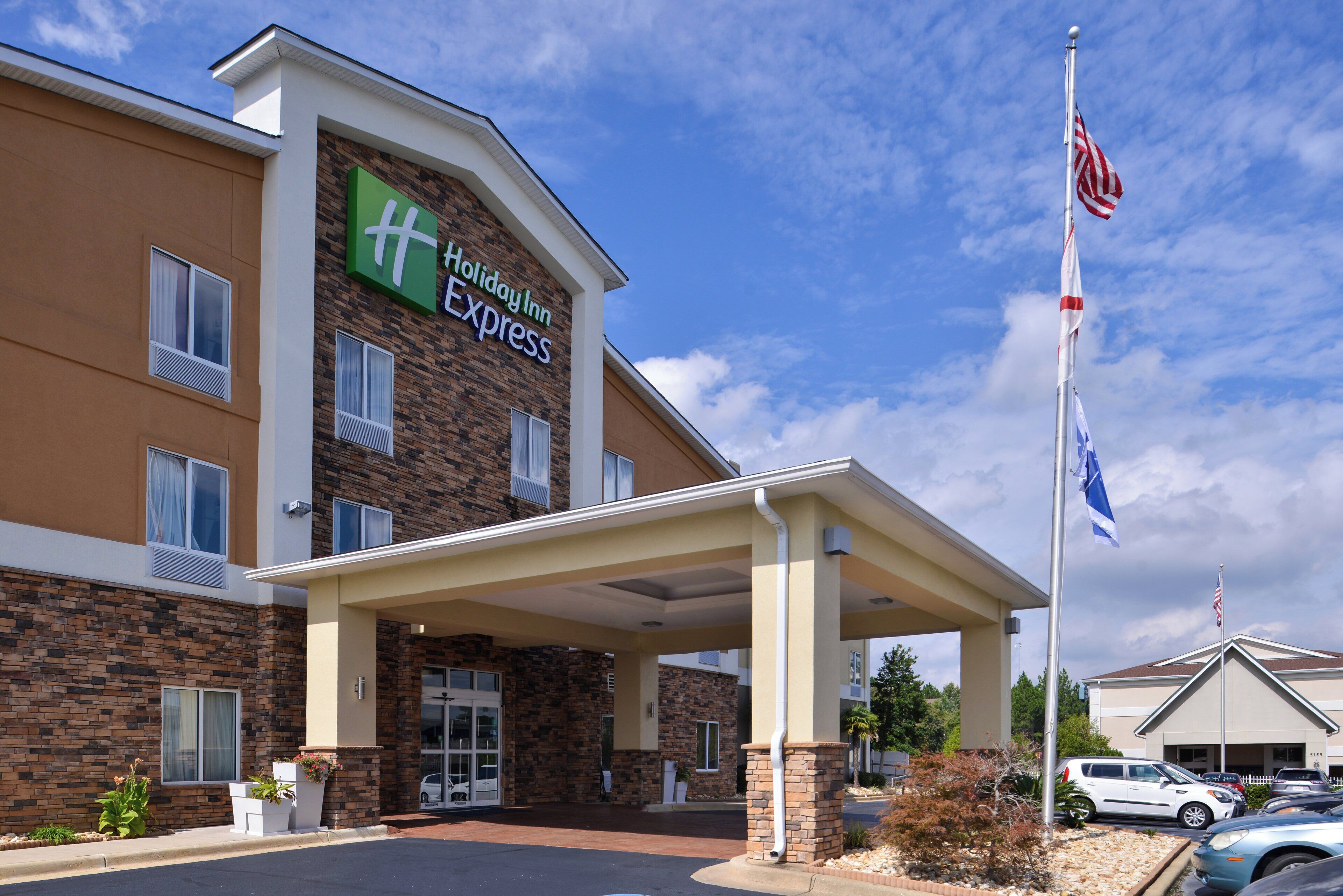 A Holiday Inn Express building with a brick facade, a covered entrance, and an American flag.