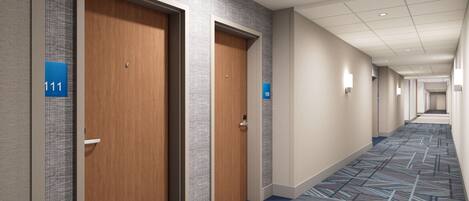 Un pasillo de hotel con dos puertas de madera, cada una con un letrero azul que indica las habitaciones 111 y 109. El pasillo tiene una alfombra estampada e iluminación empotrada.