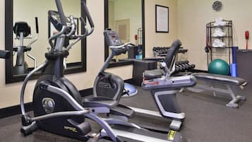 A gym with various exercise equipment including treadmills, a bench, and dumbbells.