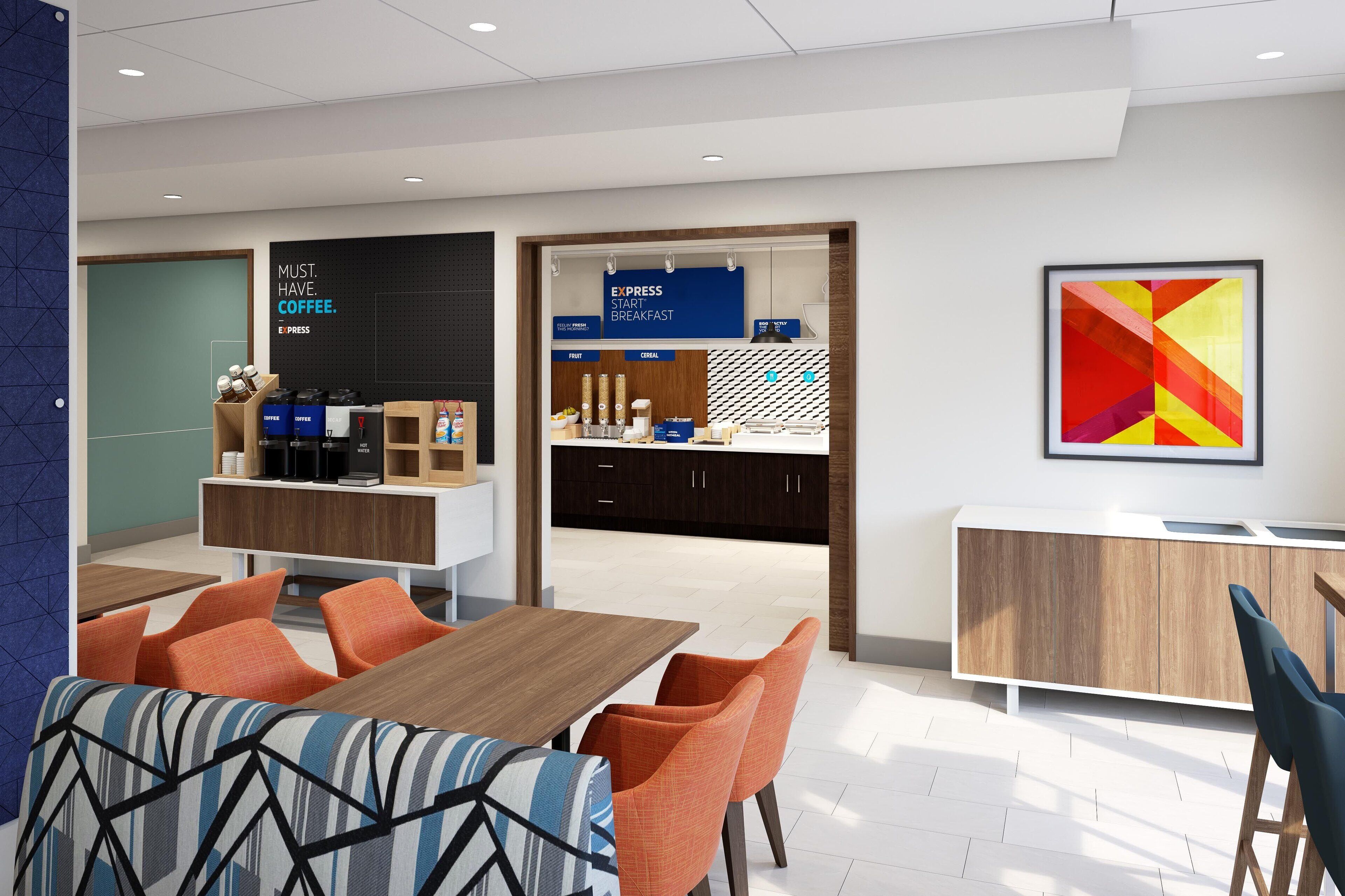 A modern dining area with a wooden table, orange chairs, and a blue wall with a geometric pattern.