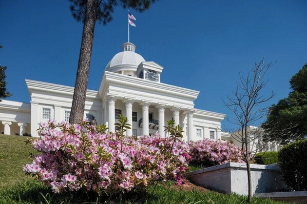 A large white building with a dome and columns, surrounded by flowering bushes. - Holiday Inn Express Montgomery - East I-85 by IHG (Montgomery)
