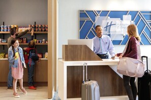 A hotel reception desk with a counter, a digital display, and a wall with geometric patterns. - Holiday Inn Express Montgomery - East I-85 by IHG (Montgomery)