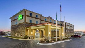 Un hotel con fachada de piedra, un acceso cubierto y un asta con banderas.