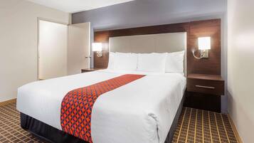 A hotel room with a large bed, a wooden headboard, two bedside tables with lamps, and a patterned floor.