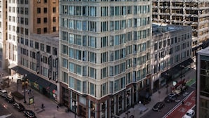 Un edificio de varios pisos con una cuadrícula de ventanas, rodeado de otros rascacielos.