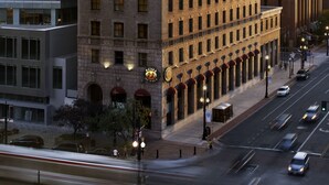 A multi-story building with a brick facade, large windows, and a visible ground-floor entrance with awnings.
