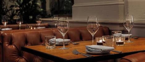 A dining table set with wine glasses, plates, and cutlery, surrounded by leather booth seating.