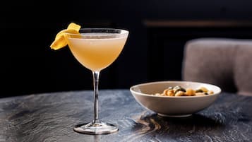 Una copa de martini con una rodaja de limón sobre una mesa de madera oscura.