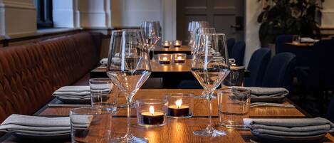 A dining table set with multiple wine glasses, a candle, and a water glass.