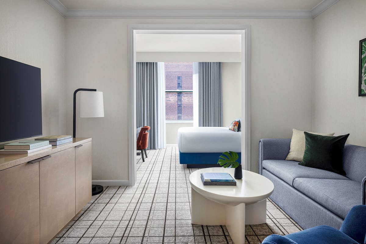 Ein modernes Hotelzimmer mit einem großen Bett, einem Sofa, einem Couchtisch und einem Fernseher auf einem Schrank.