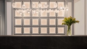 A modern interior with a marble countertop, a wall-mounted light fixture, and a vase with flowers.